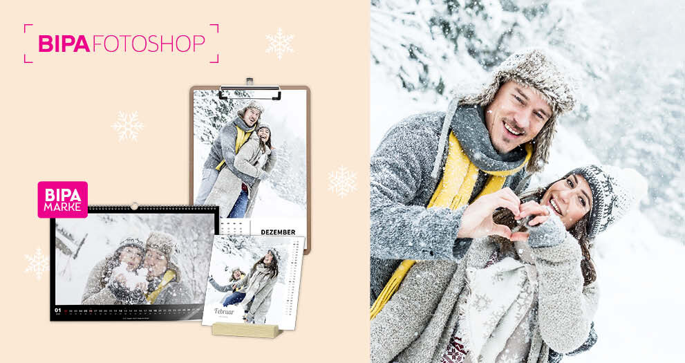 Paar im Schnee zeigt Herz mit Händen, daneben personalisierte Fotokalender mit winterlichen Bildern für 2024.