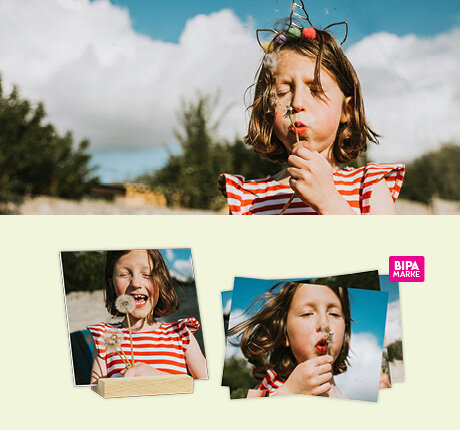 Ein Mädchen pustet lachend Pusteblumen – perfekte Frühlingsmomente als hochwertige Fotoabzüge im BIPA Fotoshop gestalten.