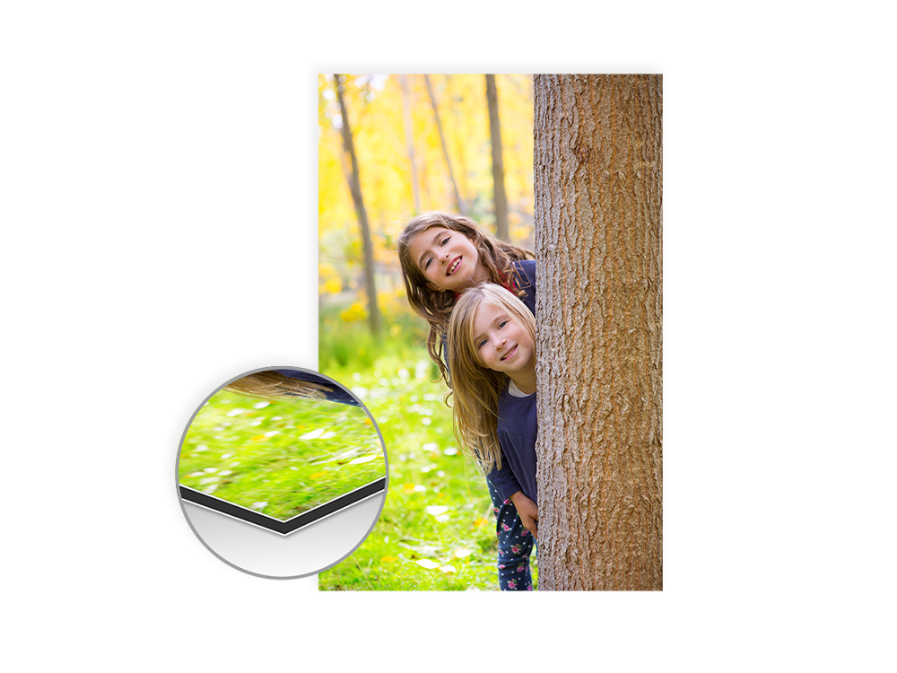 Zwei Kinder verstecken sich lachend hinter einem Baum in einer sonnigen Herbstlandschaft.